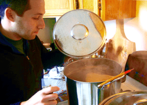 man lifting lid off homebrew kettle